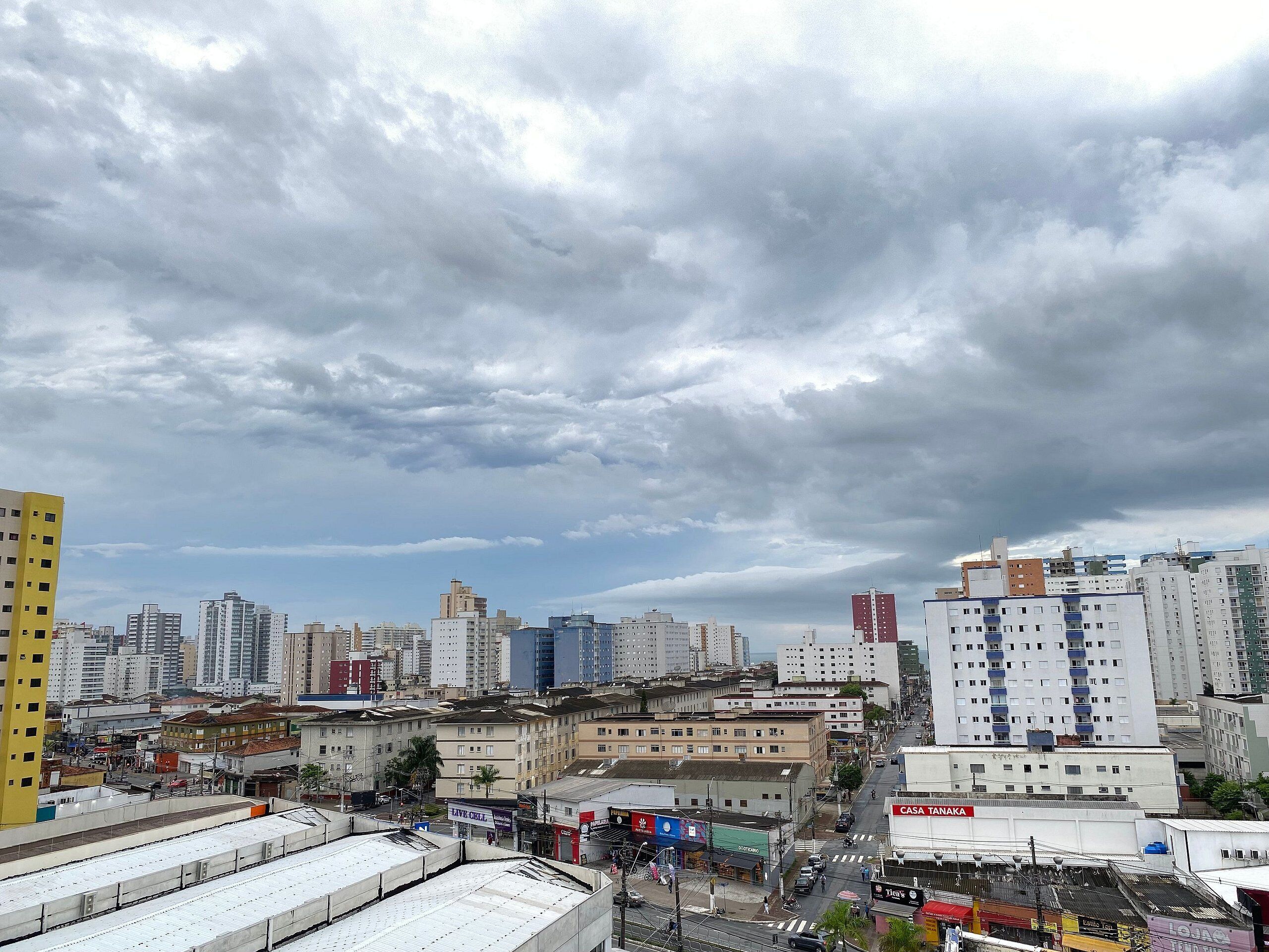 A cityscape with various buildings, including a yellow building on the left and a white building with a sign that reads "CASA TANAKA" on the right.