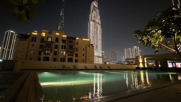 A nighttime view of a swimming pool area with a high-rise building in the background. - Burj Royale Dubai Downtown (Dubai)