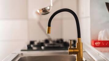 Un évier de cuisine avec un robinet moderne, une cuisinière et une boîte rouge en arrière-plan.