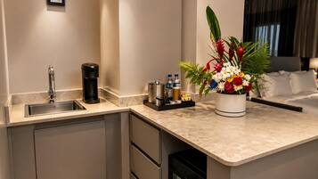 A modern kitchen with a built-in dishwasher, a coffee maker, and a small refrigerator.