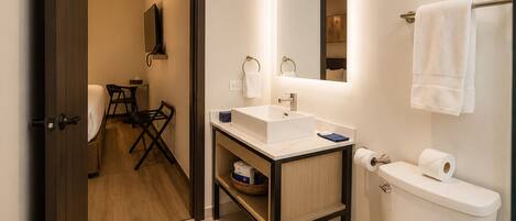 Un baño pequeño con lavamanos, espejo e inodoro blancos.