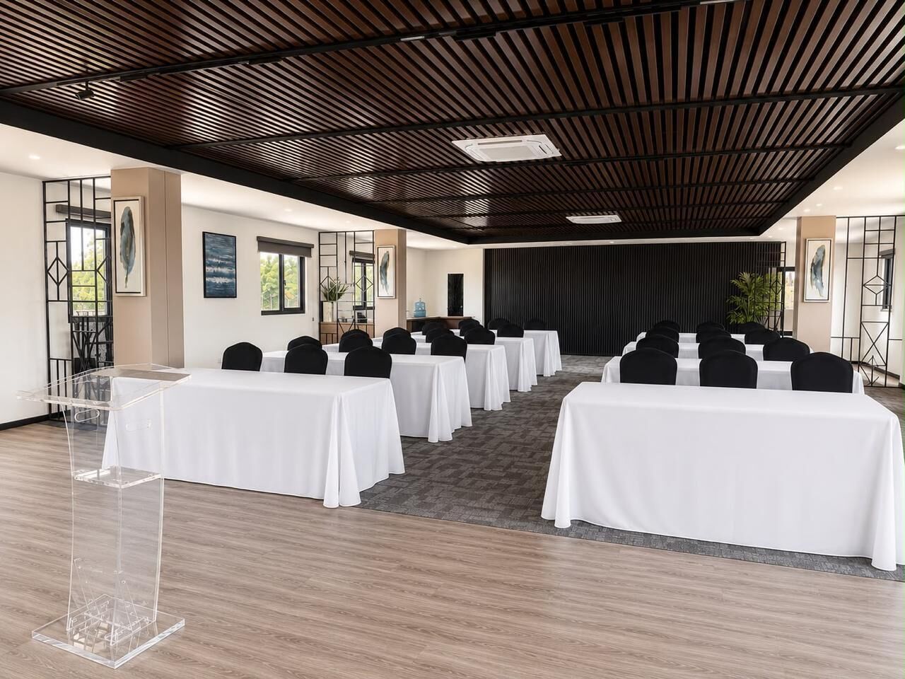A conference room with rows of tables and chairs, a podium, and a stage.