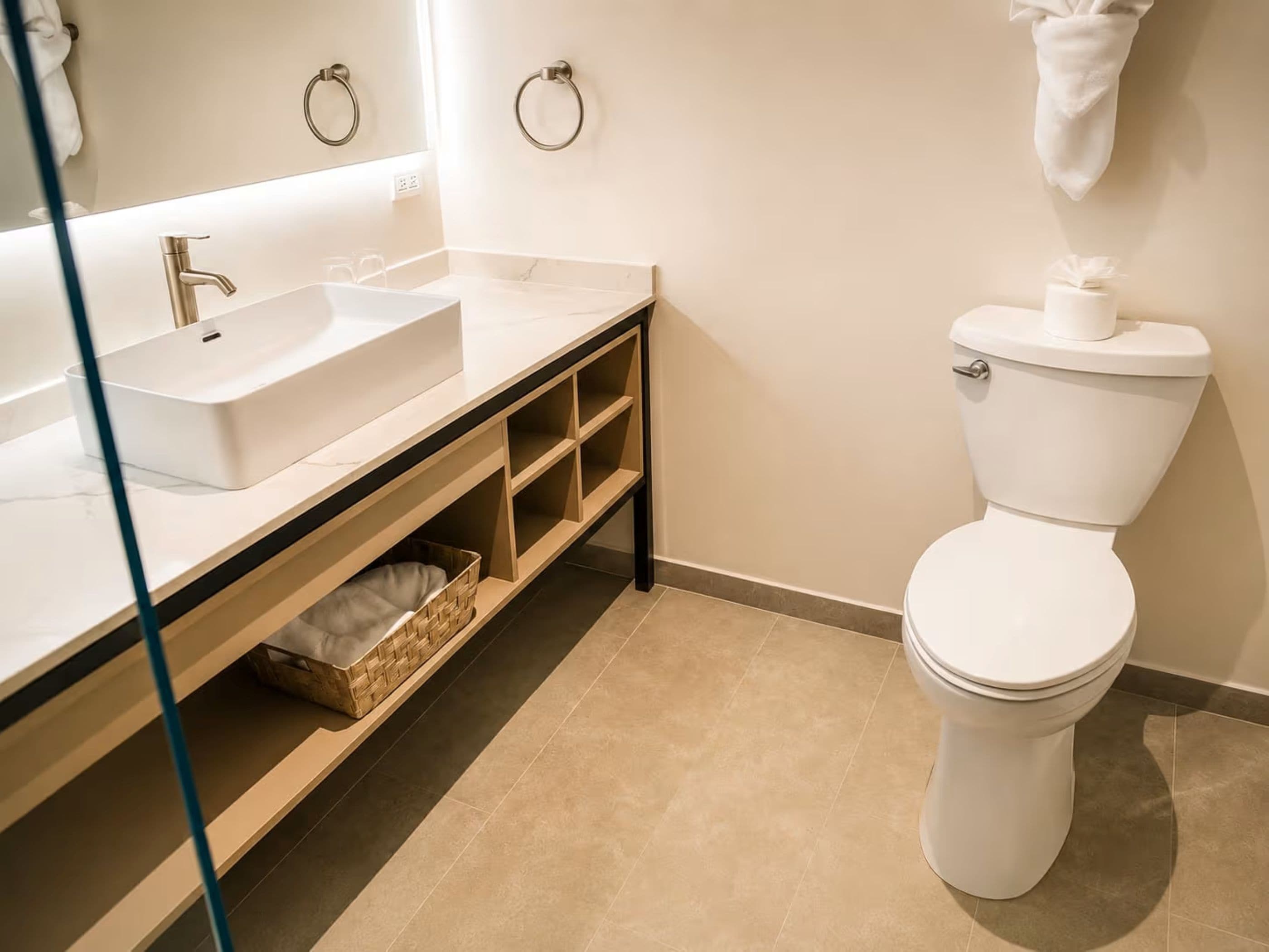 Un baño moderno con un lavabo blanco, un inodoro y un espejo.