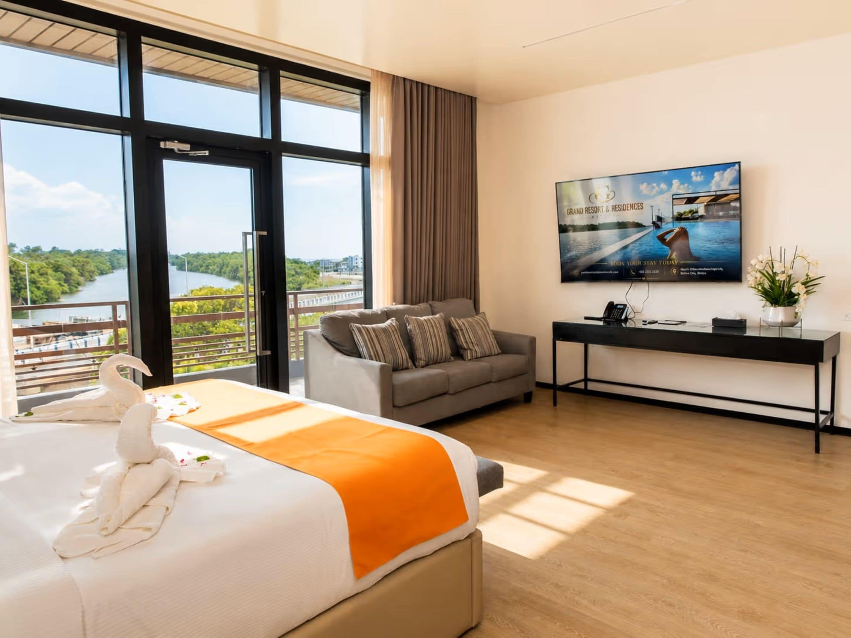 A hotel room with a large bed, a sofa, a desk, and a TV.