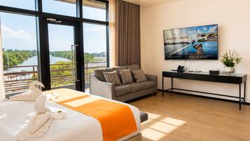 A hotel room with a large bed, a sofa, a desk, and a TV.