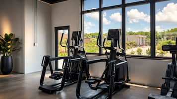 Ett gym med träningsutrustning och ett stort fönster med utsikt över omgivningen.