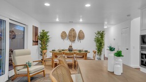 A dining area with a wooden table and chairs, surrounded by potted plants and a modern ceiling design. - Japandi Garden Home/Jacuzzi/Game Room/BBQ/Fire pit (San Jose)