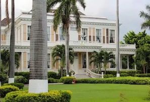 A large, two-story building with a symmetrical facade, a central entrance, and a balcony on the upper floor.