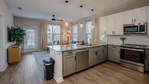 A modern kitchen with stainless steel appliances, a central island, and pendant lighting. - Brand new apartment, 10 minutes from Downtown w/Pool|Wi-Fi|Publix|Free Parking (Athens)