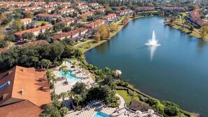 Ett bostadsområde med en stor sjö, en fontän och en swimmingpool med solstolar.