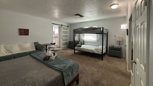 A bedroom with bunk beds, a sofa, a desk, and a chair.