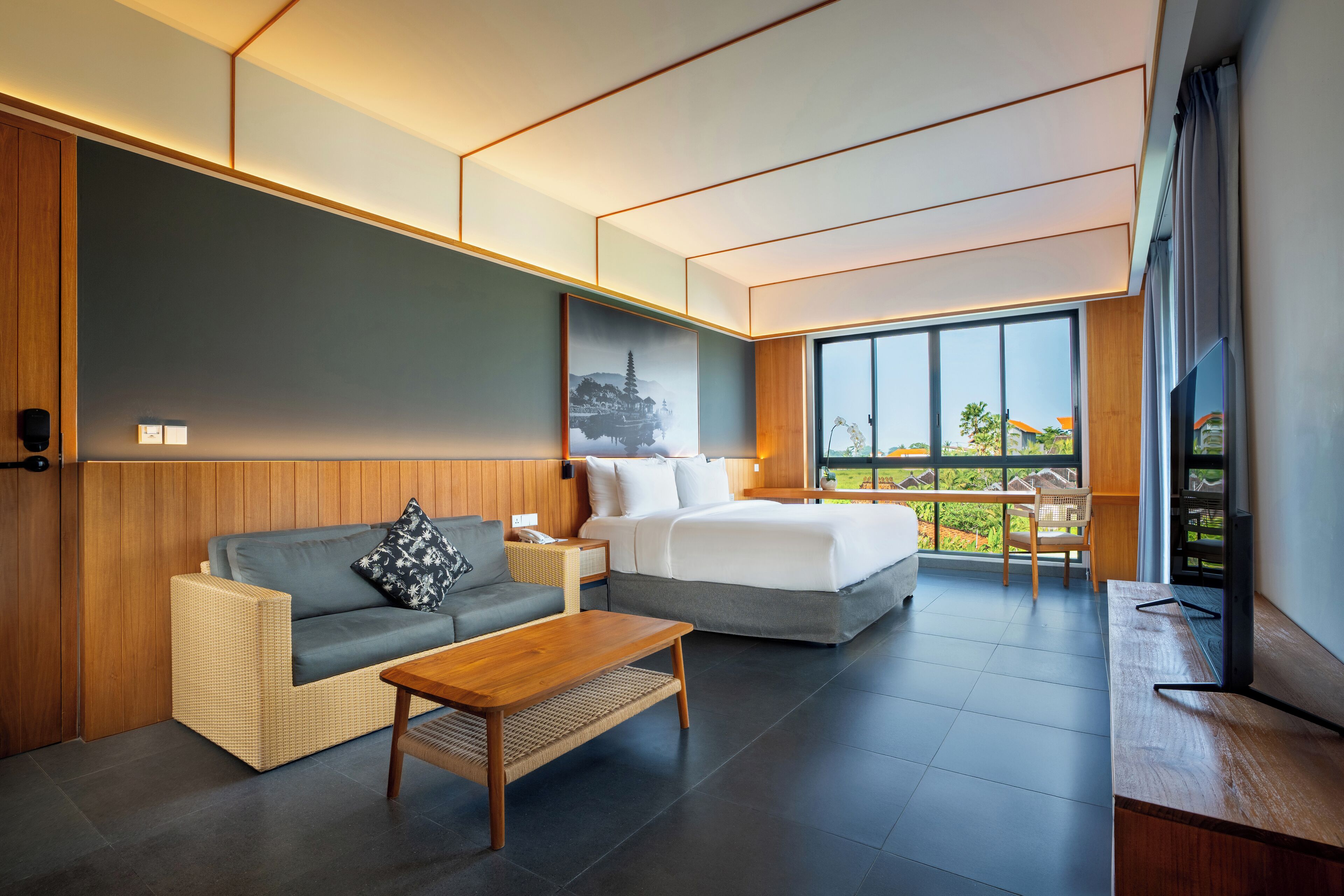 Une chambre d’hôtel moderne avec un grand lit, un canapé, une table basse en bois et un téléviseur.
