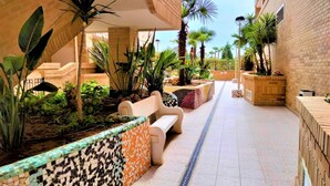 A corridor with benches, potted plants, and a tiled floor. - ACV - Costa Azahar I-2nd line 3rd floor 3 north 2 (OROPESA)
