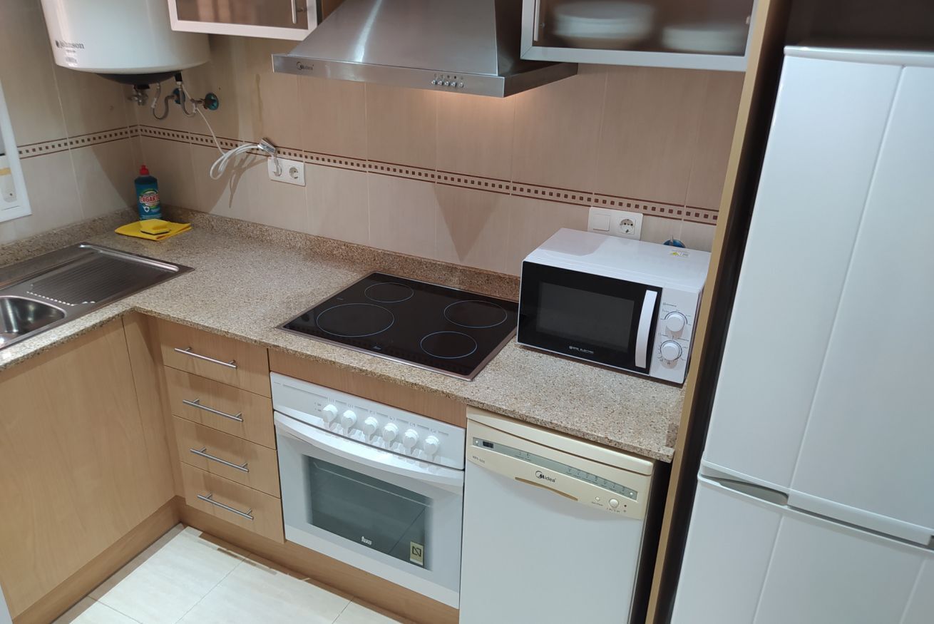 A compact kitchen with a stove, microwave, oven, dishwasher, and a sink.