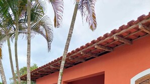 A building with a red exterior, a tiled roof, and a small porch area with a wooden door and window. - Angra dos Reis - Beachfront House - Praia de Fora - East End (Unknown)
