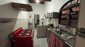 A compact kitchen with a red gas stove, a microwave, and a sink. - Angra dos Reis - Beachfront House - Praia de Fora - East End (Unknown)