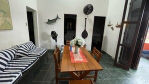 A dining area with a wooden table and chairs, a striped sofa, and decorative wall hangings. - Angra dos Reis - Beachfront House - Praia de Fora - East End (Unknown)