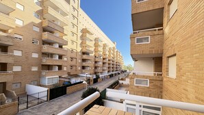 Un immeuble résidentiel à plusieurs étages, doté de balcons, d’une cour intérieure et offrant une vue sur un ciel dégagé.