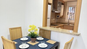 Une table à manger avec quatre chaises, une plante en pot et deux verres posés sur des sets de table.