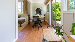 A cozy room with a dining area, a sofa, and a large window with a view of greenery. - Exclusive 2 Bed Standalone Villa in St Albans (Christchurch)