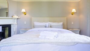 A hotel room with a large bed, two bedside tables, a fireplace, and two wall-mounted lamps. - Exclusive 2 Bed Standalone Villa in St Albans (Christchurch)