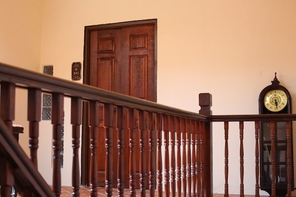 A wooden staircase with a railing, a wooden door, and a wall-mounted clock. - Penang Story Linn House (George Town)