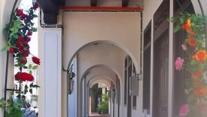 A corridor with arches, red carpet, and hanging flowers. - Penang Story Linn House (George Town)