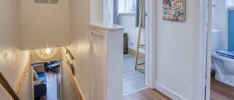 Un escalier avec une rampe en bois, un canapé bleu et une petite table avec une horloge au mur.