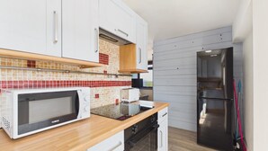 A modern kitchen with white cabinets, a microwave, a toaster, and a stainless steel refrigerator.