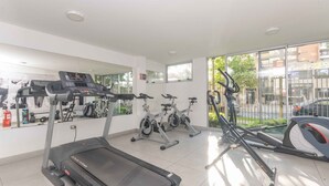 Un gimnasio con caminadora, bicicletas estáticas y máquinas elípticas.