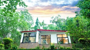 A two-story house with large windows and a brick facade, surrounded by lush greenery. - amã Stays & Trails Writer's Hill Nahan, Sirmaur Himachal (Nahan)