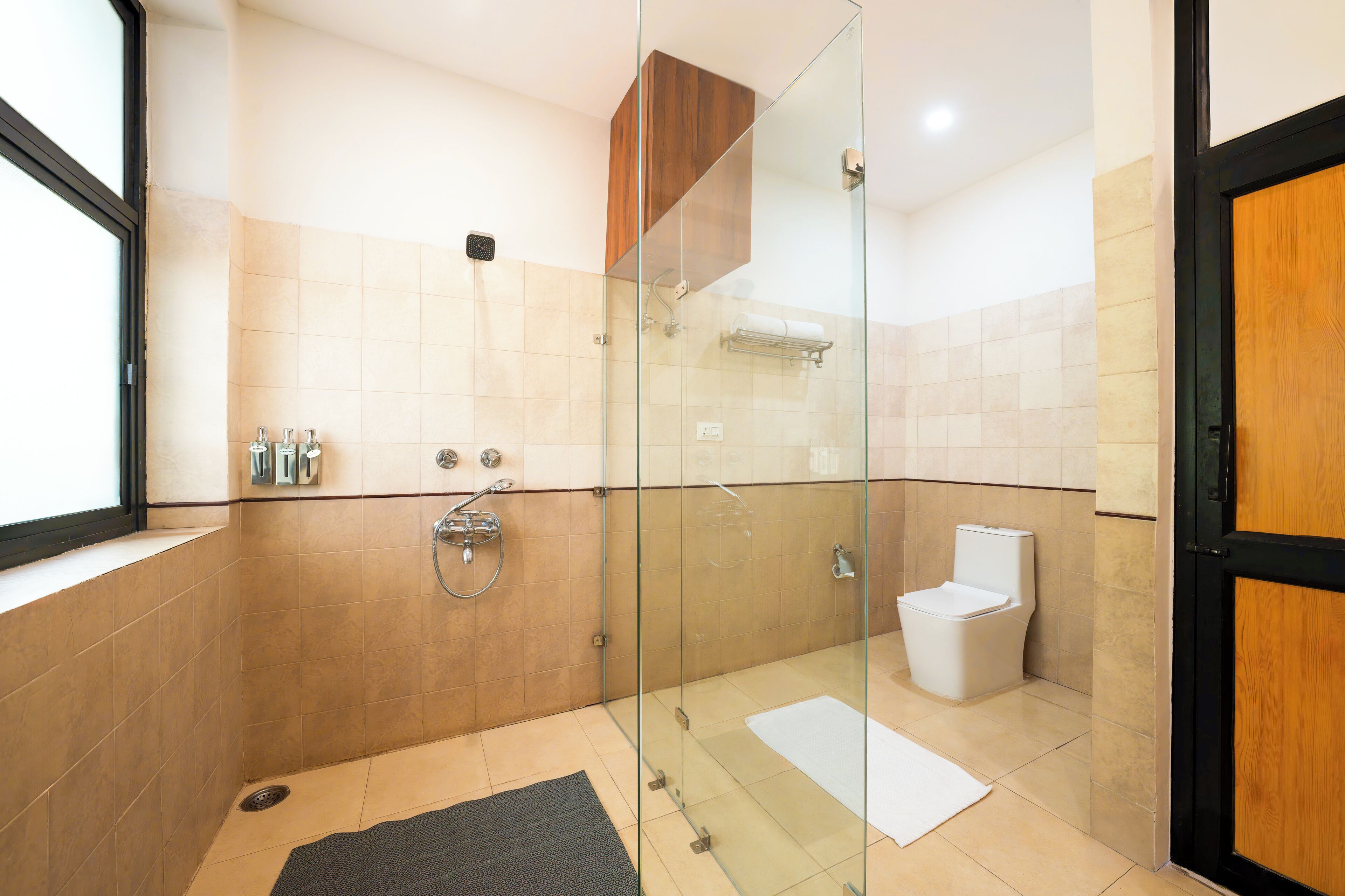 A modern bathroom with a glass-enclosed shower, a toilet, and a towel rack.