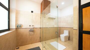 A modern bathroom with a glass-enclosed shower, a toilet, and a towel rack.