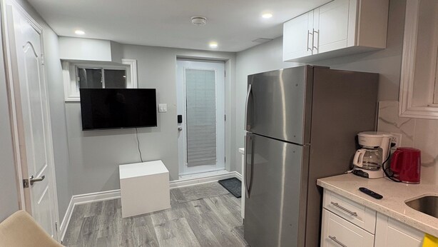 A compact kitchen with a refrigerator, coffee maker, and a chair. - Brand new 1 bedroom Fully Furnished apartment (Brampton)