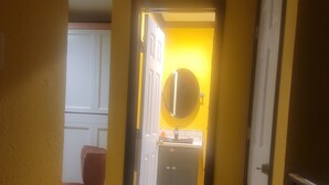 A hallway with a yellow wall, a white door, and a mirror on the wall. - Houston Sweet spot Town house in shadows of downtown skyscrapers' w/rooftop view (Houston)