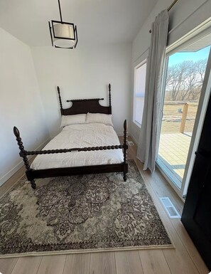Relax in a serene bedroom with a four-poster bed, bedside lamp, and sliding glass door leading to an outdoor area.