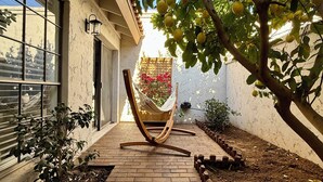 A brick pathway leading to a hammock chair, a small tree with lemons, and a white building with large windows. - Central Scottsdale- Spanish style patio home -2bd 2ba 2 car garage -on bike path (Scottsdale)