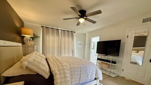 A bedroom with a bed, a ceiling fan, a TV, and a door. - Central Scottsdale- Spanish style patio home -2bd 2ba 2 car garage -on bike path (Scottsdale)