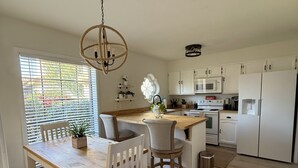 A modern kitchen with white cabinets, a wooden dining table, and a hanging light fixture. - Central Scottsdale- Spanish style patio home -2bd 2ba 2 car garage -on bike path (Scottsdale)