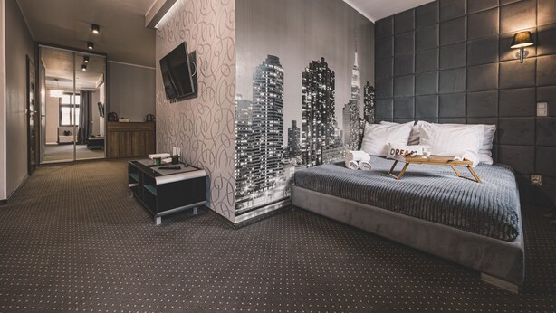 Une chambre à coucher moderne avec une fresque représentant un paysage urbain, un grand lit et une table de chevet.
