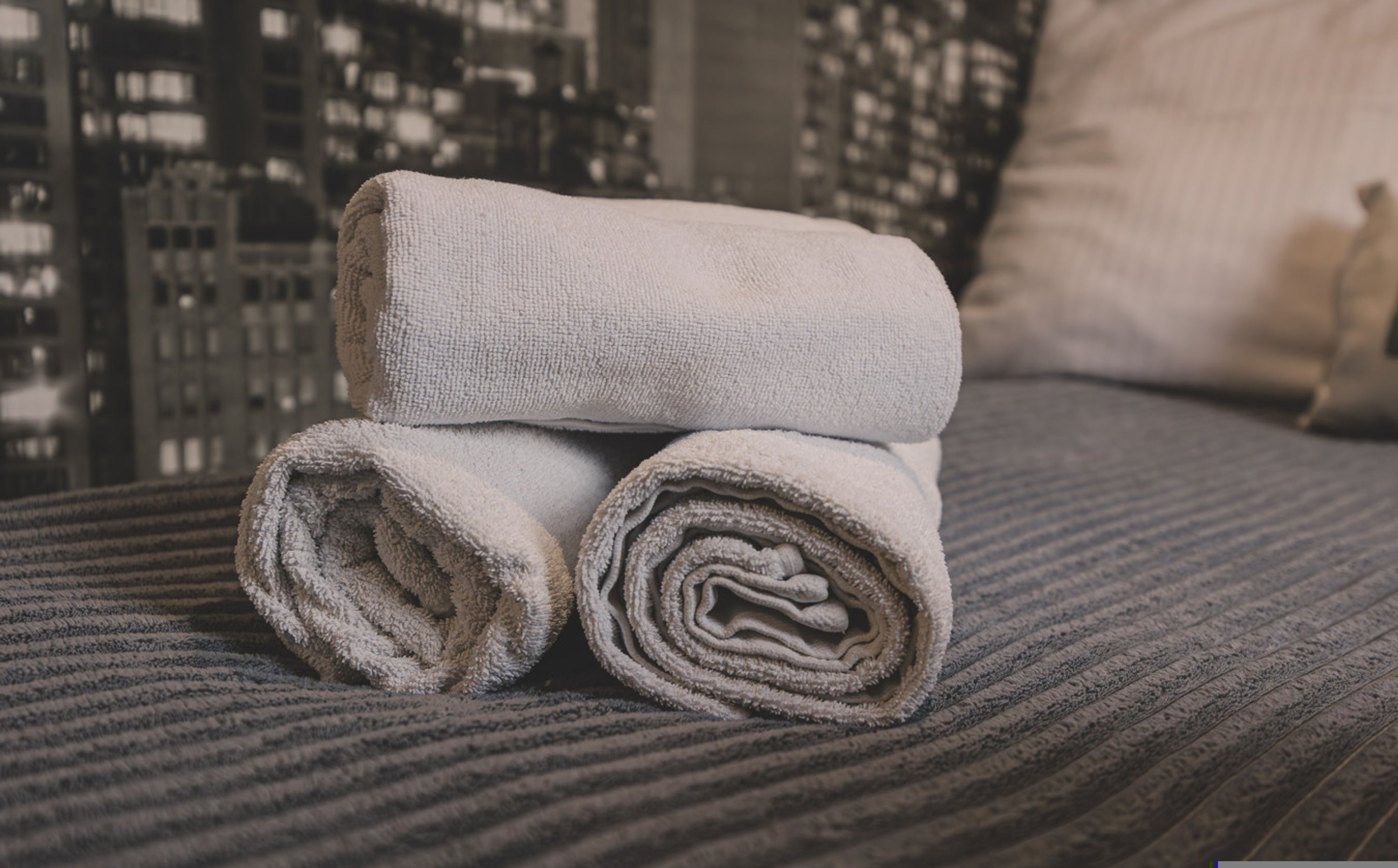 A neatly folded towel stacked on a textured bedspread.