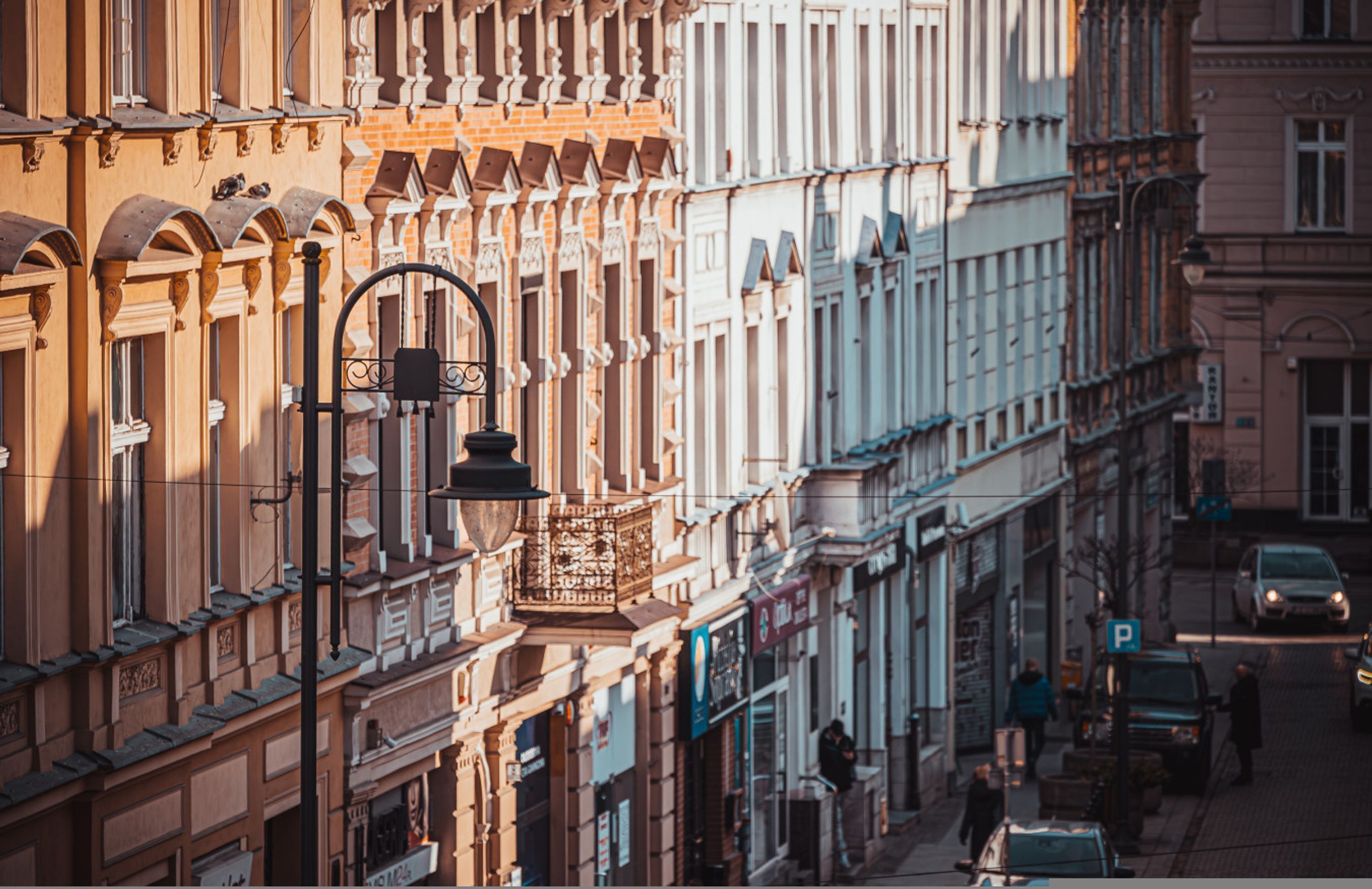 A street view with buildings featuring classic architecture, a street lamp, and a parked car.