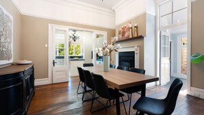 A dining area with a wooden table, black chairs, and a vase of flowers. - Secret Garden - historic charm meets Bowral vibe (Bowral)