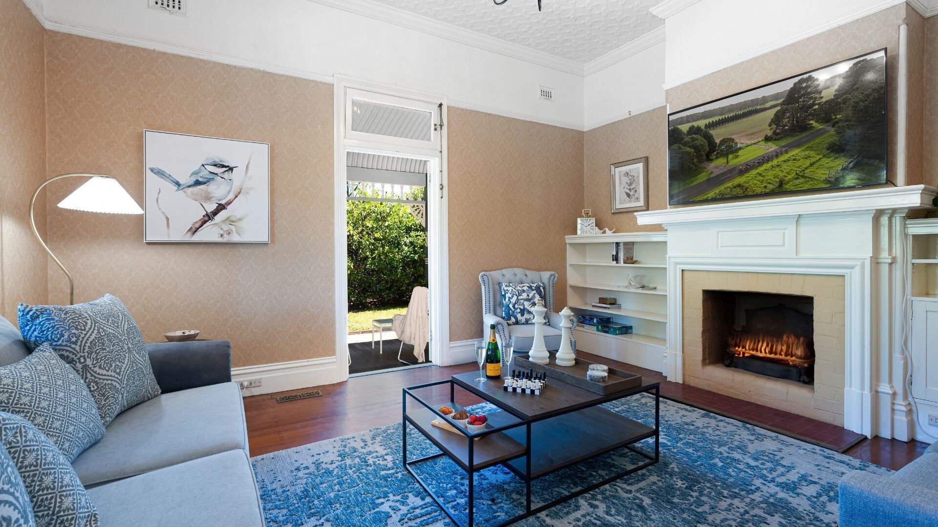 Un salon avec une cheminée, un canapé, une table basse et un tableau au mur.