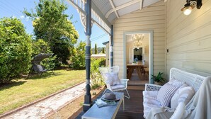 A covered porch with a dining table and chairs, a bench, and a potted plant. - Secret Garden - historic charm meets Bowral vibe (Bowral)