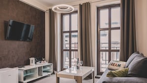 A modern living room with a flat-screen TV, a coffee table, a sofa with a 'DREAM' pillow, and a large window with curtains. - Dream 23A Studio z Przeszklon Azienk Centrum (Bydgoszcz)