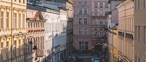 A narrow street lined with historic buildings, a casino, and parked cars.