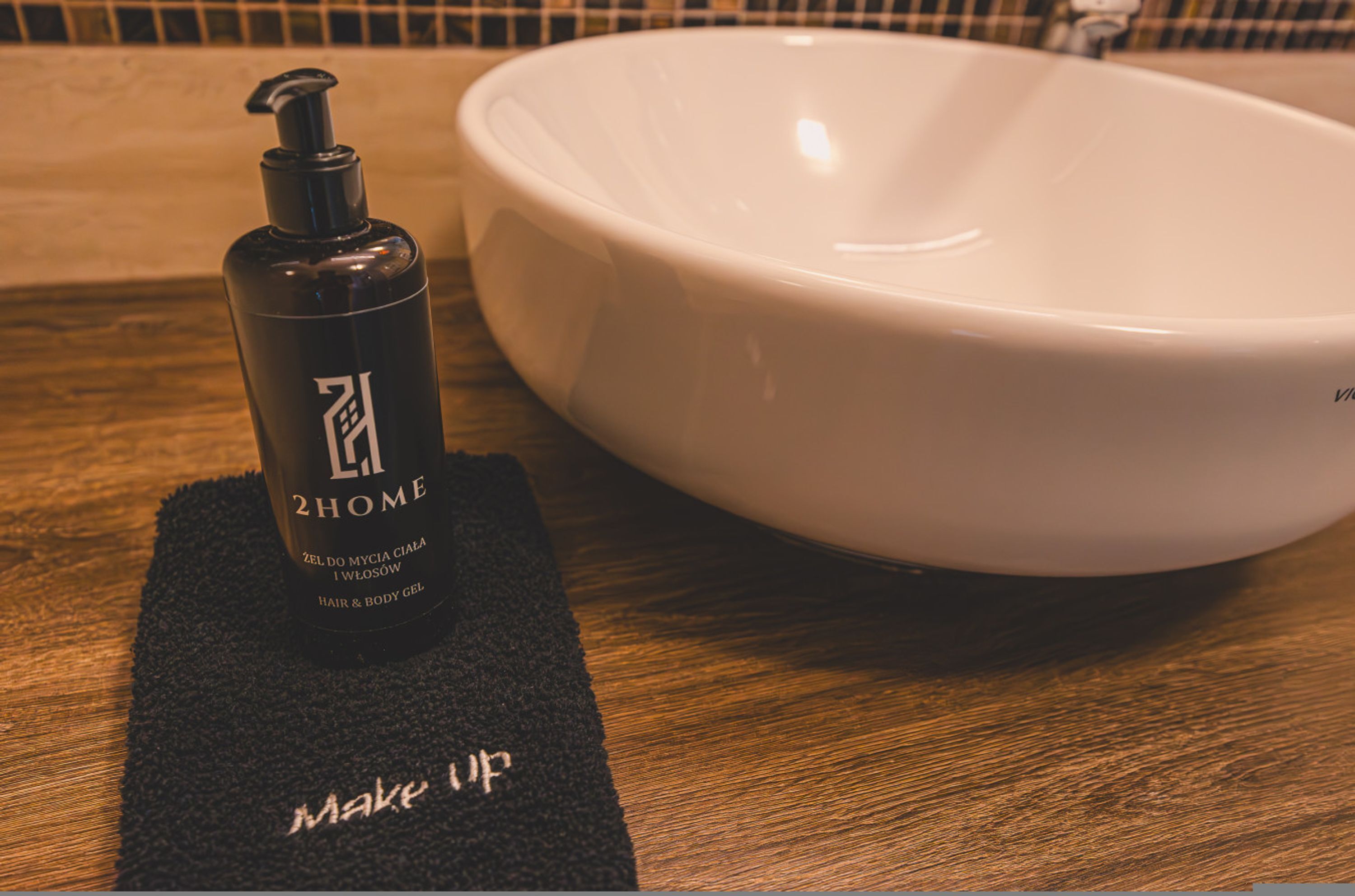 Un lavabo de salle de bain avec un flacon de gel pour les cheveux et le corps posé sur un tapis noir sur lequel est écrit « maquillage ».
