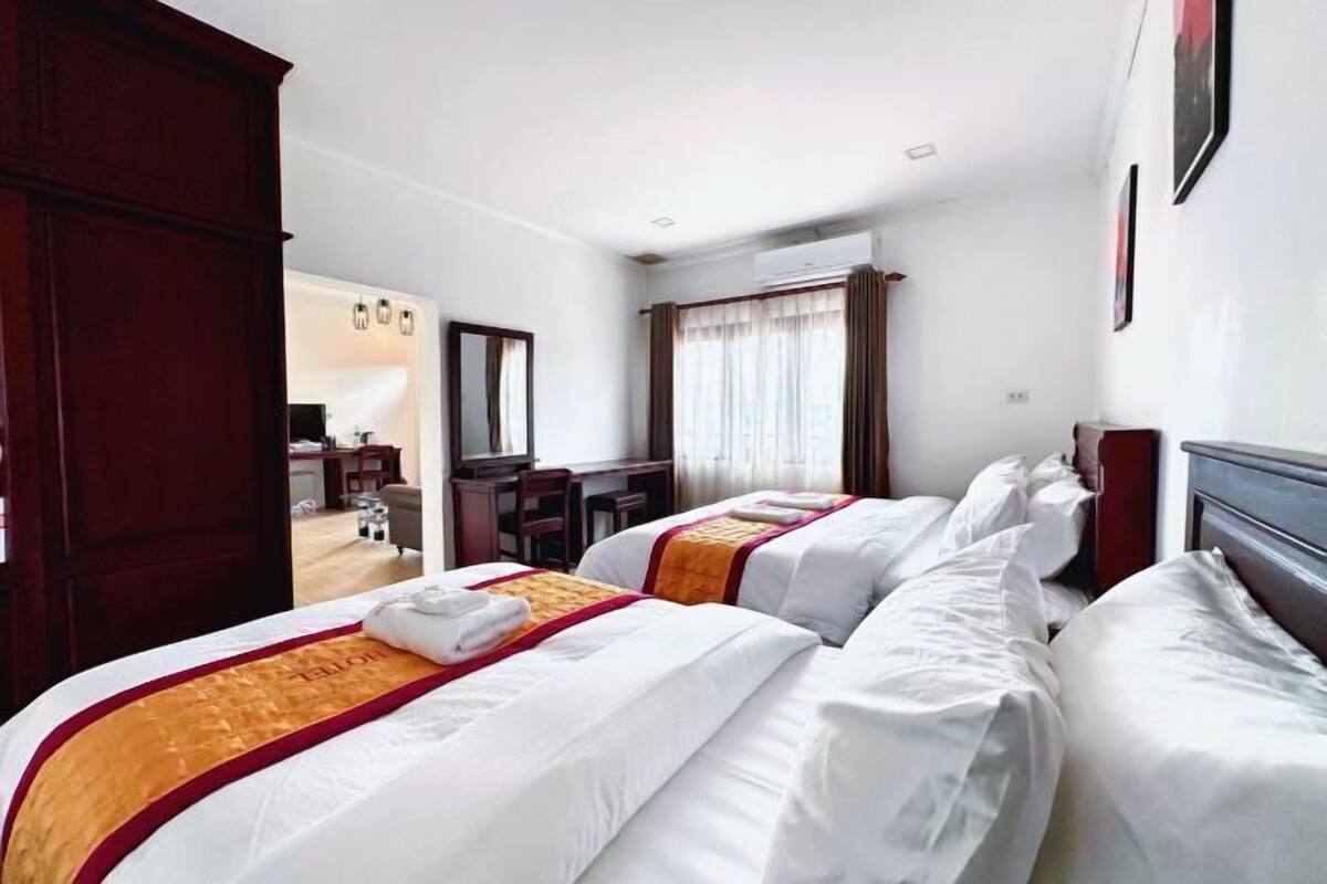 A hotel room with two beds, a desk, and a chair.