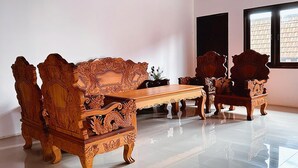 A room with ornate wooden furniture, including a sofa and chairs, with a tiled floor and a window with blinds. - Vang Vieng Family Boutique Hotel (Vang Vieng)